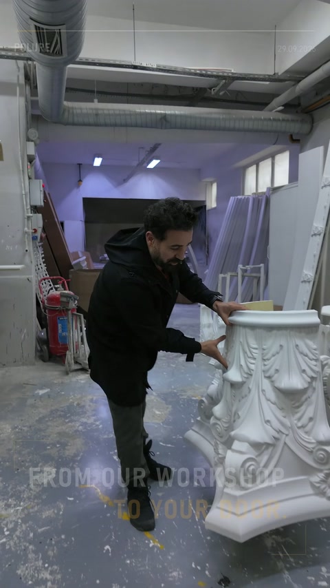 Il maestro controlla la superficie del capitello corinzio bianco in officina.