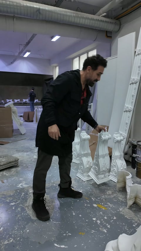 Il maestro estrae dalla rastrelliera un elemento decorativo lungo e curvato.