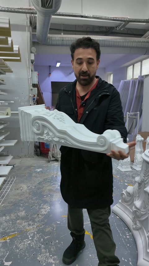 Il produttore mostra la superficie ampia della cornice ornamentale con entrambe le mani.