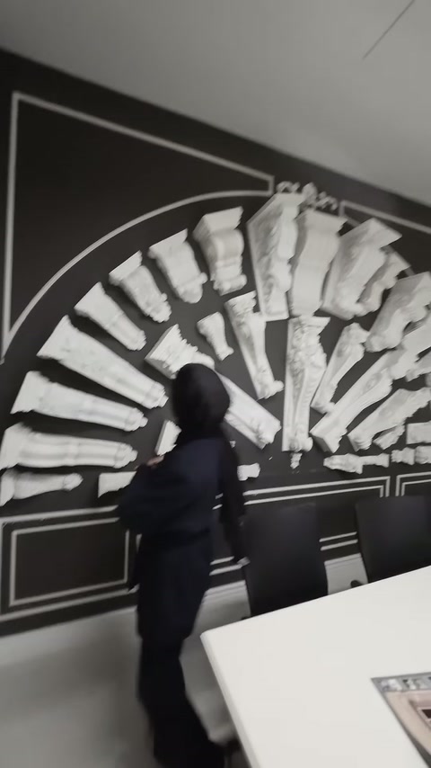 Sunucu, duvara dizilmiş farklı biçimlerdeki cephe payandalarını inceliyor.