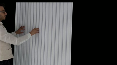 Applicator holds white wall panel sample in vertical position.