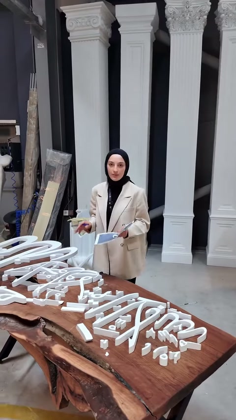 Il presentatore indica con la mano le lettere tagliate personalizzate sul tavolo in legno.