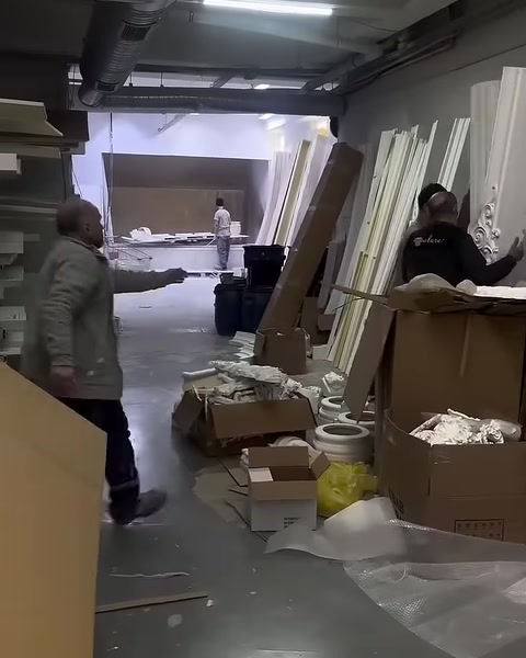 Long profiles, product pieces and packaging boxes are visible in the workshop