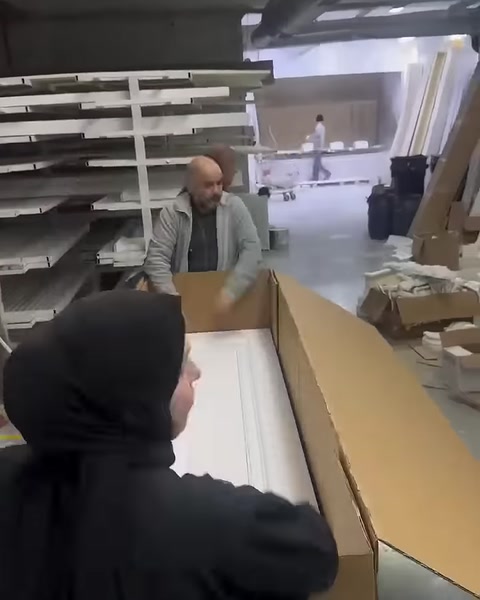Long white decorative profiles are arranged side by side inside a cardboard box
