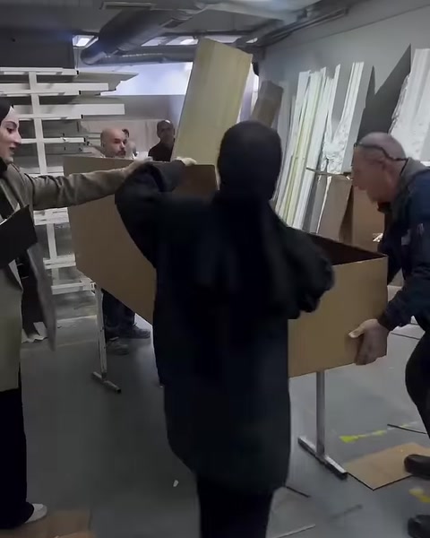 Workers arrange the cardboard flaps of a long product box