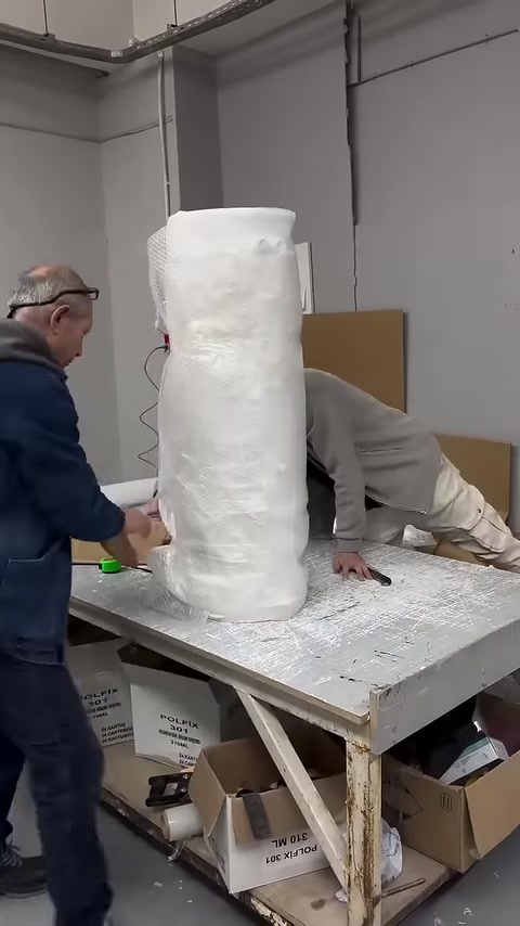 A decorative column body wrapped in protective material is placed on a workbench
