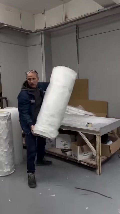 The packaged decorative column body is carefully lifted from the workbench