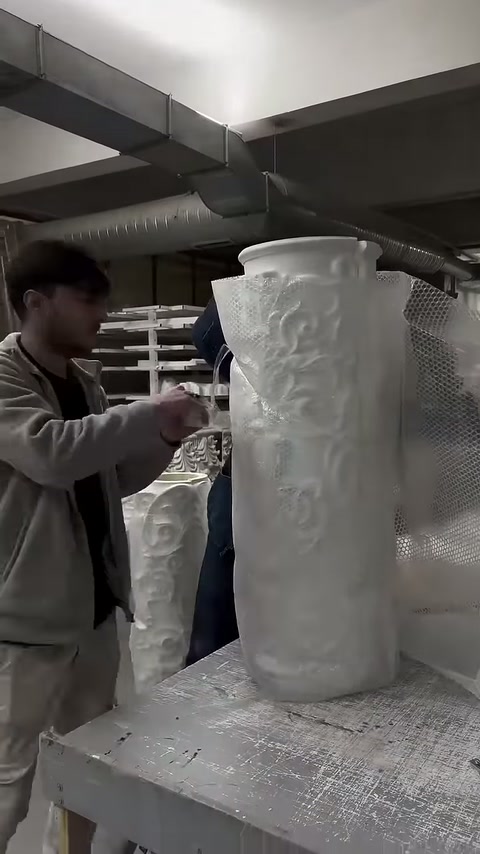Worker inspecting the outer surface of an embossed column piece by hand at the workshop