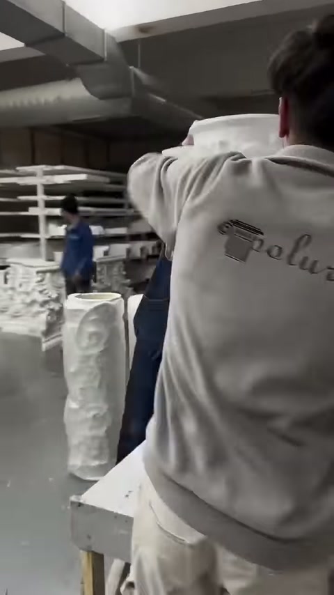 Two workers wrapping white protective cover around the column body
