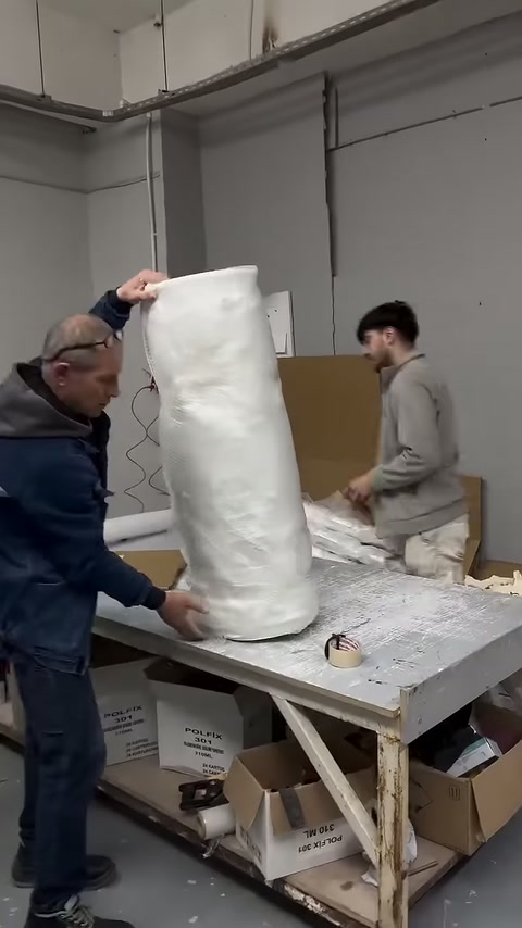 Protective packaging of the column body being completed by two workers