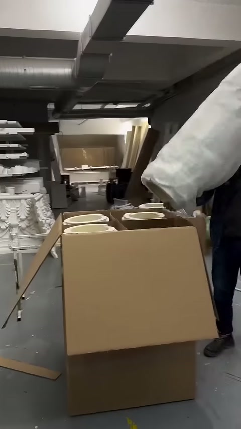 Wrapped column piece being moved toward an open cardboard box