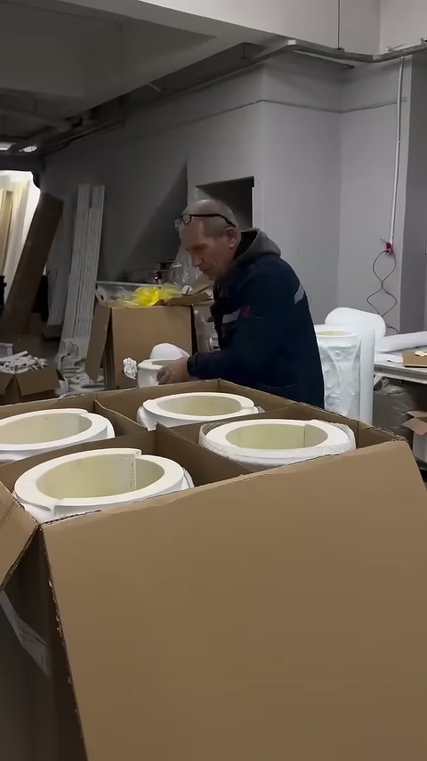 Worker inspecting the placement of circular column pieces inside the box