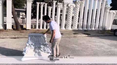 A staff member examining an ornamental white column capital placed on the ground
