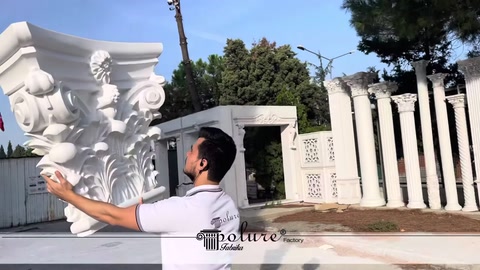 A staff member holding a large patterned column capital outdoors