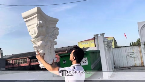 A tall white column capital displayed outdoors