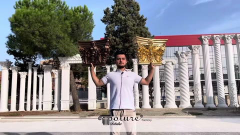 A staff member holding a gold classical column capital overhead