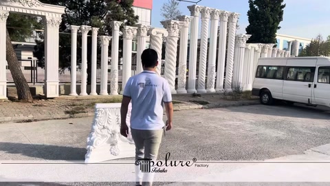 White Corinthian column capital displayed on the ground in an outdoor setting