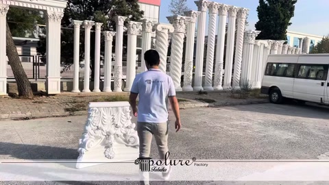 Staff member walking toward a white column capital in an open area
