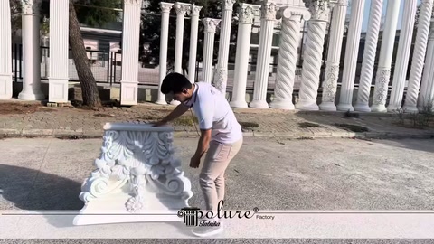 Staff member grasping an ornamental column capital and preparing to lift it