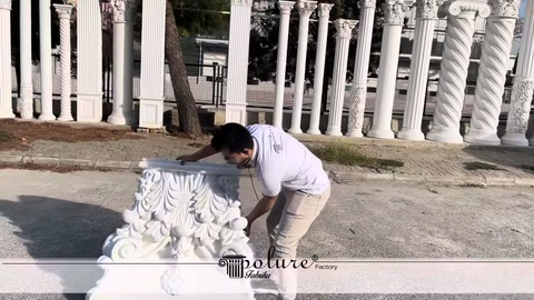 Staff member continuing to lift a Corinthian motif capital from the ground