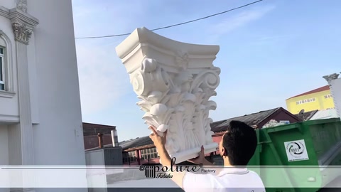 Corinthian column capital held at height against a building facade
