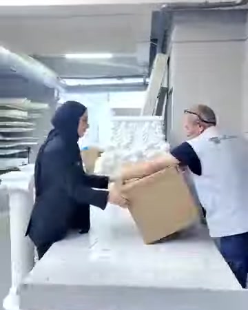 Due operatori sistemano elementi decorativi bianchi all'interno della scatola