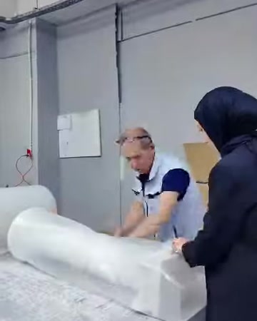 Due operatori avvolgono insieme un grande prodotto decorativo sul banco di imballaggio