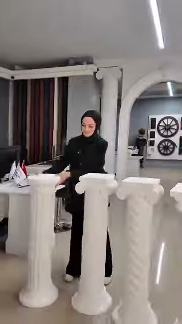L'addetto fornisce spiegazioni accanto a basi con dettagli a spirale e scanalature.