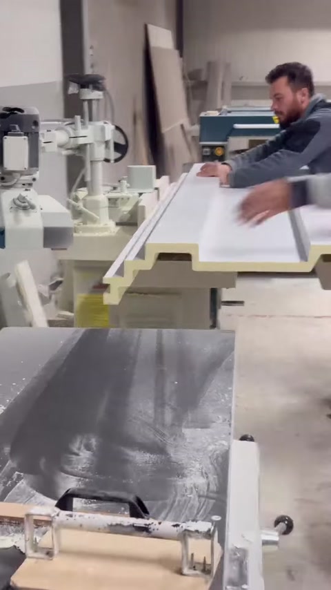 The facade band molding profile is guided and machined by hand on the machine table.