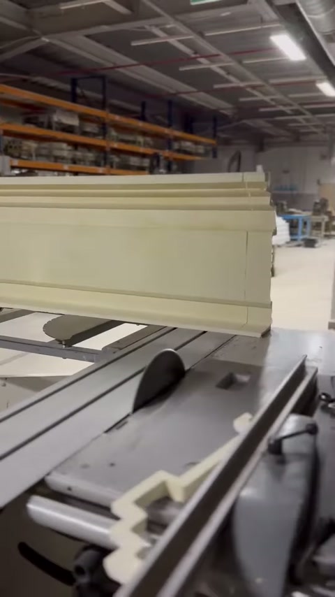 The profile's wide surface advances horizontally in front of the cutting machine.