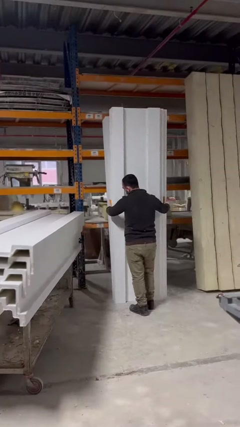 The craftsman carefully slides the long profile piece over the machine in a controlled manner.