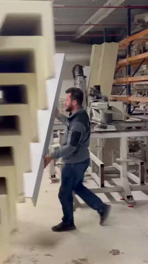 The worker arranges large standing polyurethane pieces next to the shelf.