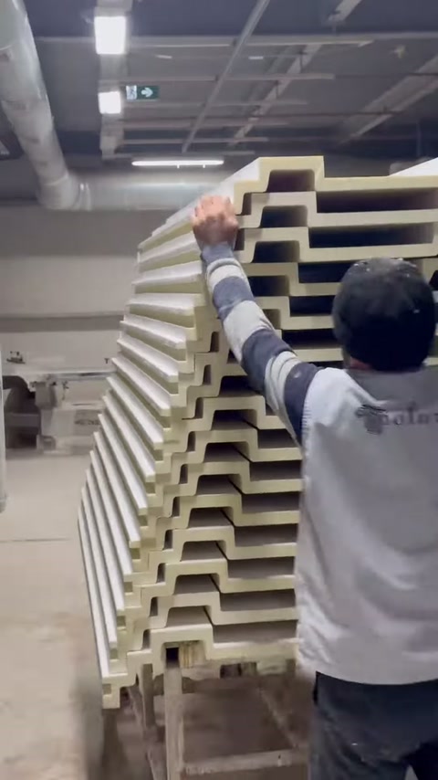 The worker checks the open cut edges of the stacked profiles by hand.