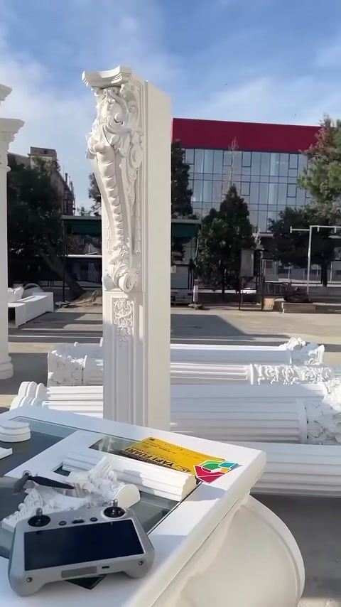 An ornamental white column element is exhibited in an open-air display area