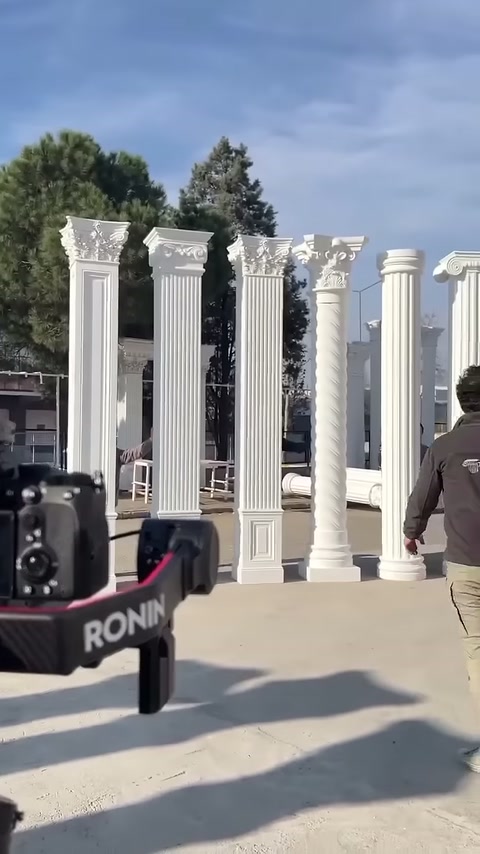 A camera and a worker are seen in front of the white column series