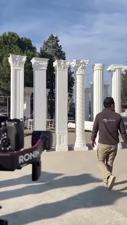 A worker moves toward the decorative column display positioned in front of the camera