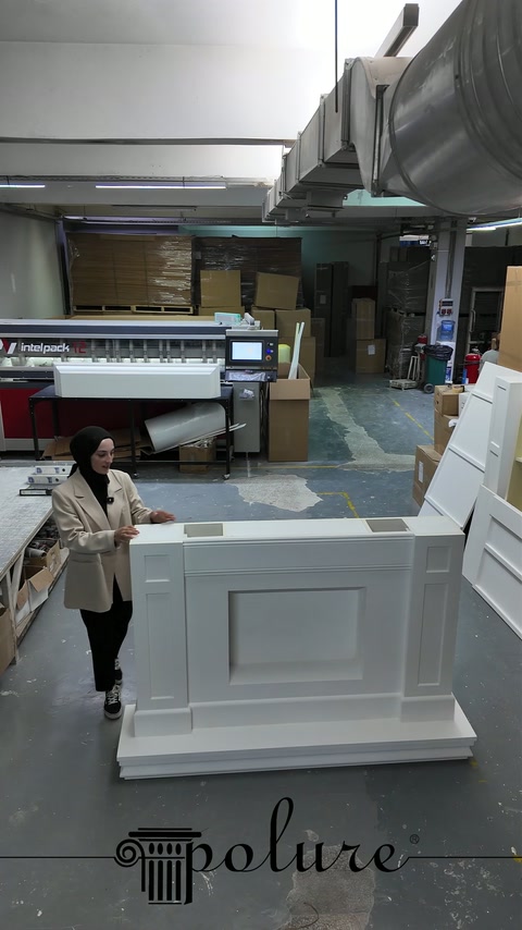 Modulo anteriore bianco di un camino decorativo in poliuretano viene tenuto in posizione verticale in laboratorio.