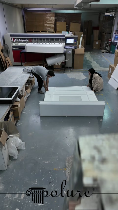 Gli operai si chinano in laboratorio per assemblare i moduli decorativi del camino sul pavimento.