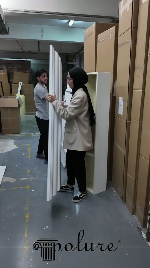 Gli elementi profilati dei bordi del camino vengono trasportati verticalmente dai lavoratori in laboratorio.