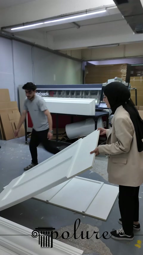 Gli operai in laboratorio dirigono l'ampio pannello verso le parti del camino sul pavimento.