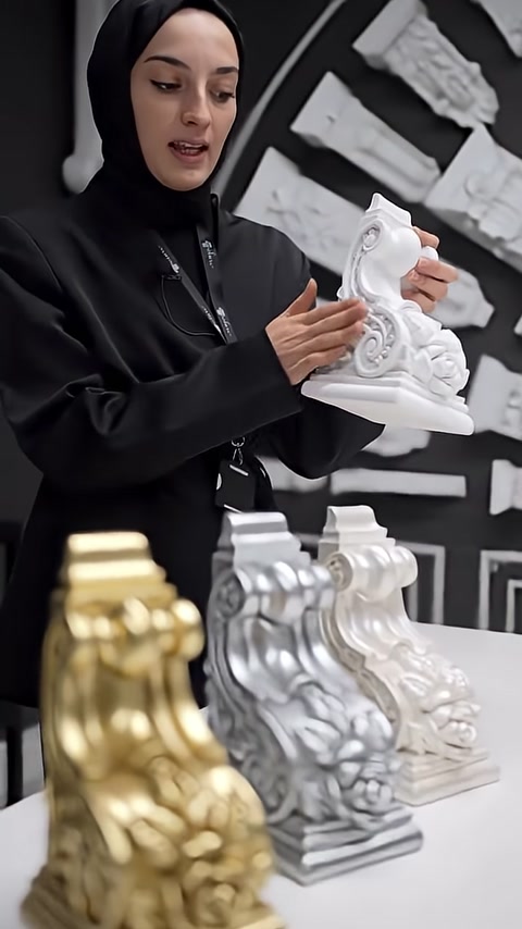 A white-primed corbel model with curved motifs is displayed by hand