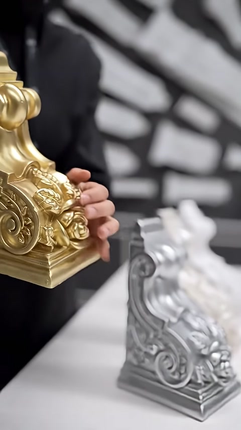 The curved raised patterns of a gold-colored corbel are shown in close-up