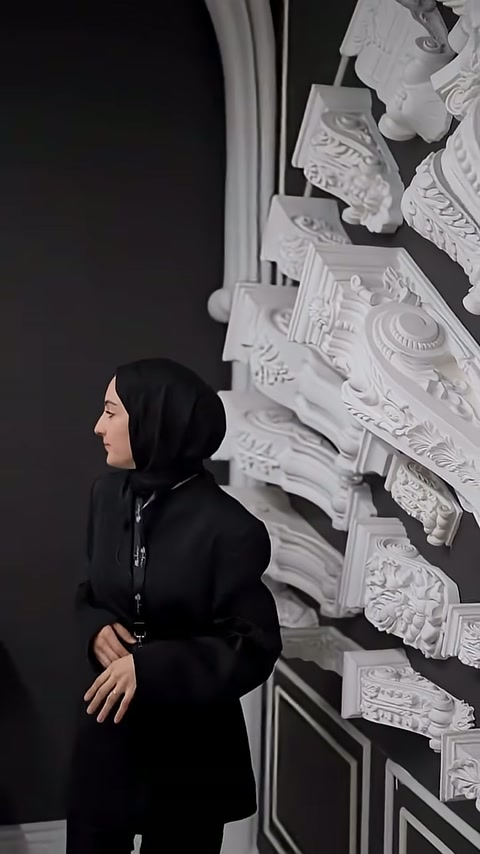 Il presentatore estende la mano verso il grande elemento decorativo posizionato orizzontalmente