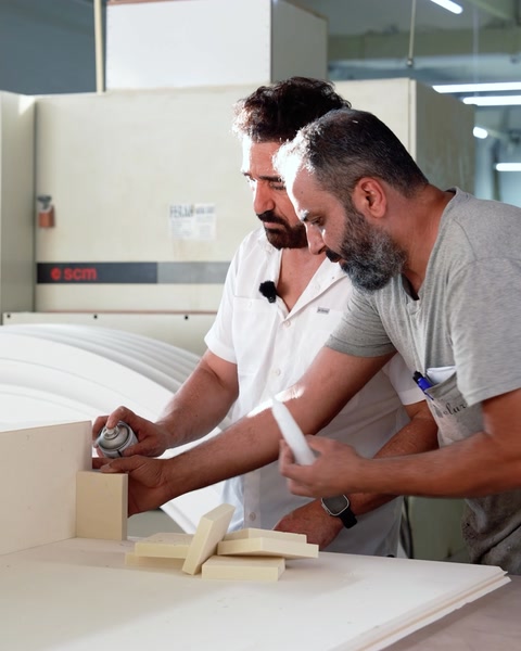 Due artigiani allineano e incollano un profilo ad arco con una squadra sul banco di lavoro