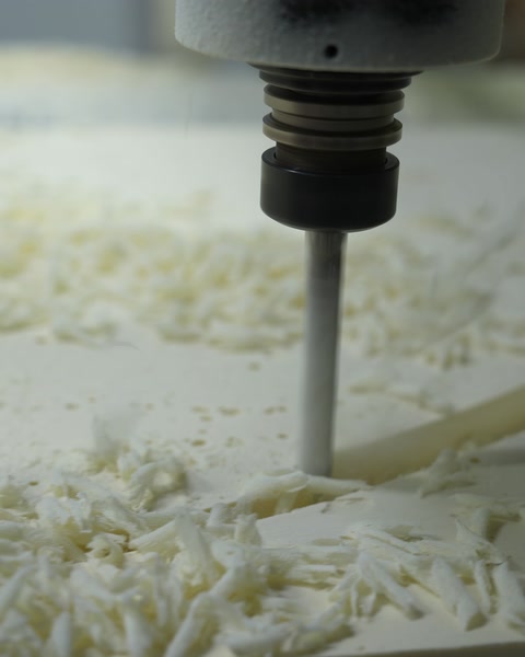 Una fresa CNC lavora la superficie di uno stampo in poliuretano, producendo trucioli