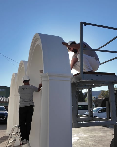Il team installa un grande elemento ad arco sulla facciata esterna con una scala