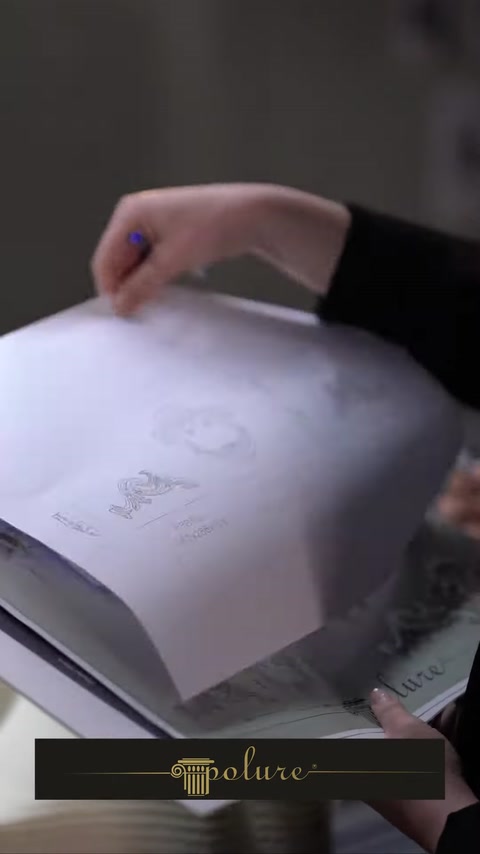 Hand opening a printed project catalog with architectural sketches