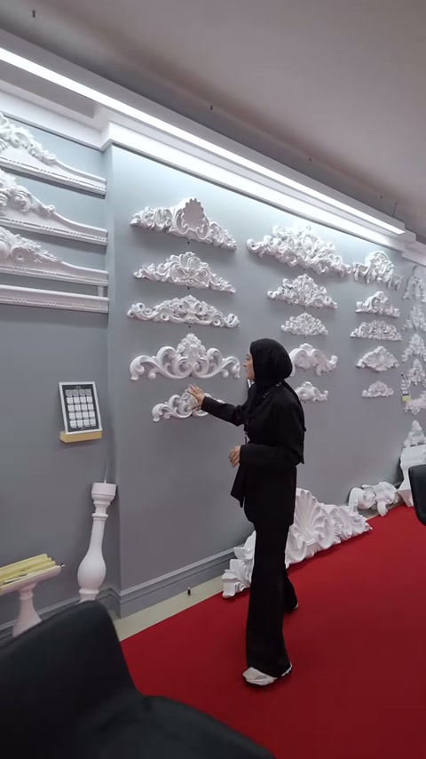 Çok sayıda kıvrımlı taç motifi gri sergileme duvarında inceleniyor.