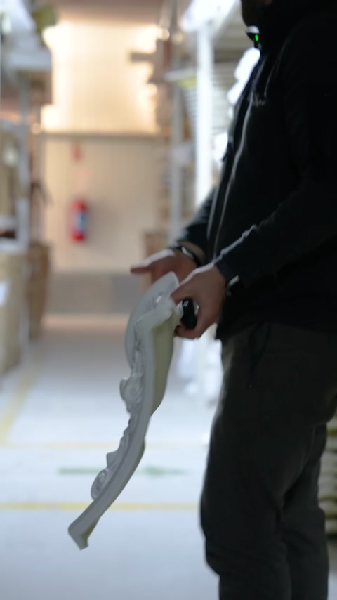 Un sottile profilo ornamentale curvo in poliuretano viene tenuto in posizione verticale
