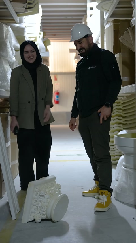 Two workers inspect a floor decoration element in the production corridor